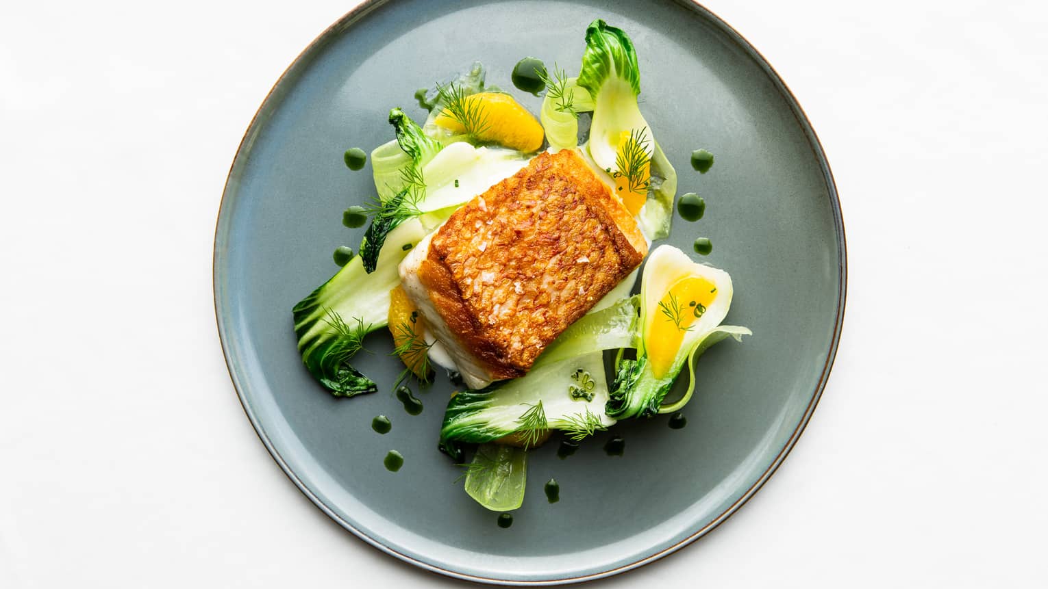 Aerial view of Florie's Seared Snapper Fillet on bed of bok choy and orange slices 