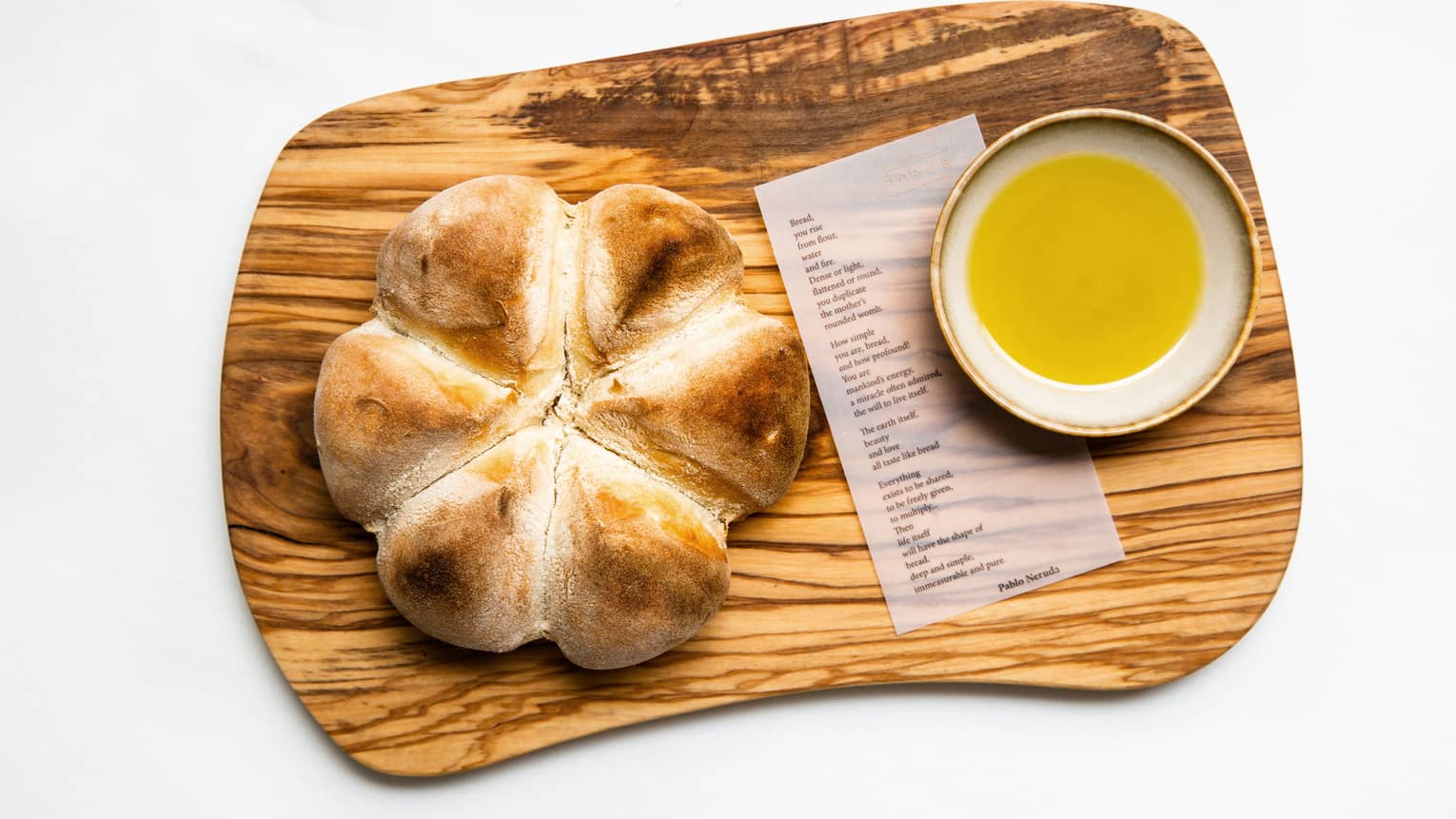 Round bread and melted butter on a small wooden plate.