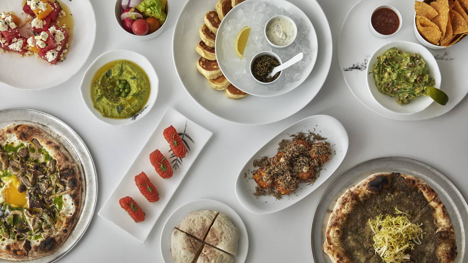 An aerial view of various dishes on a crisp white table 