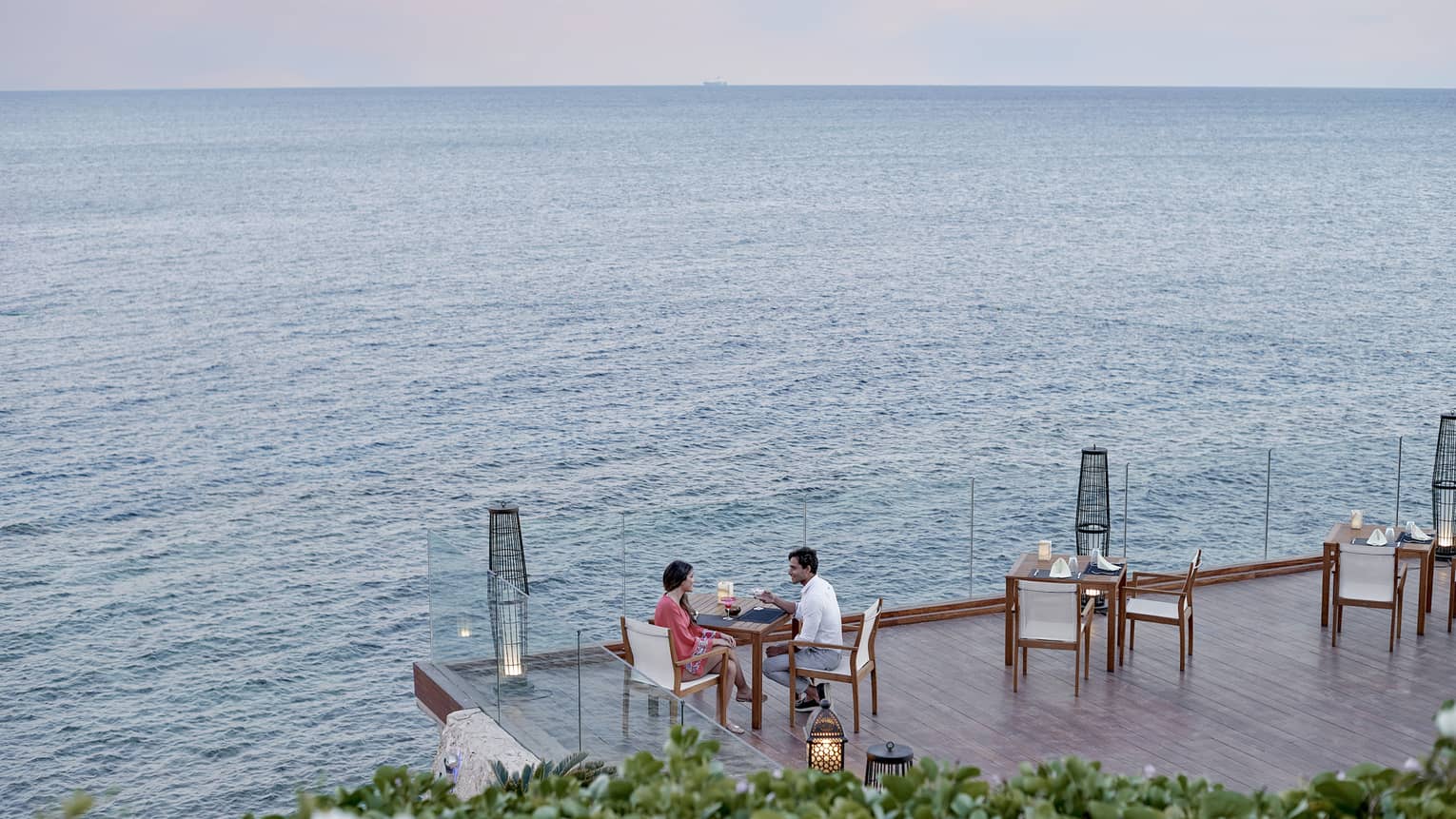 Couple at patio dining table on deck overlooking water
