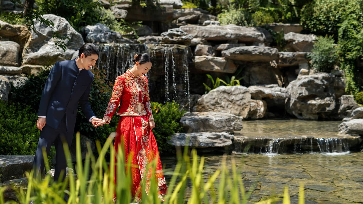 Mand and woman walk together in a garden with waterfall
