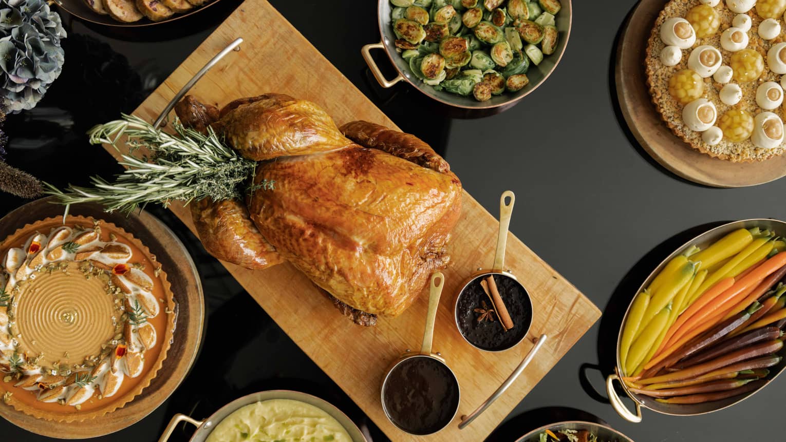 Table set with a roasted turkey, Brussels sprouts, sliced carrots and various other dishes for a holiday meal,Table set with a roasted turkey, Brussels sprouts, clived carrots and various other dishes for a holiday meal