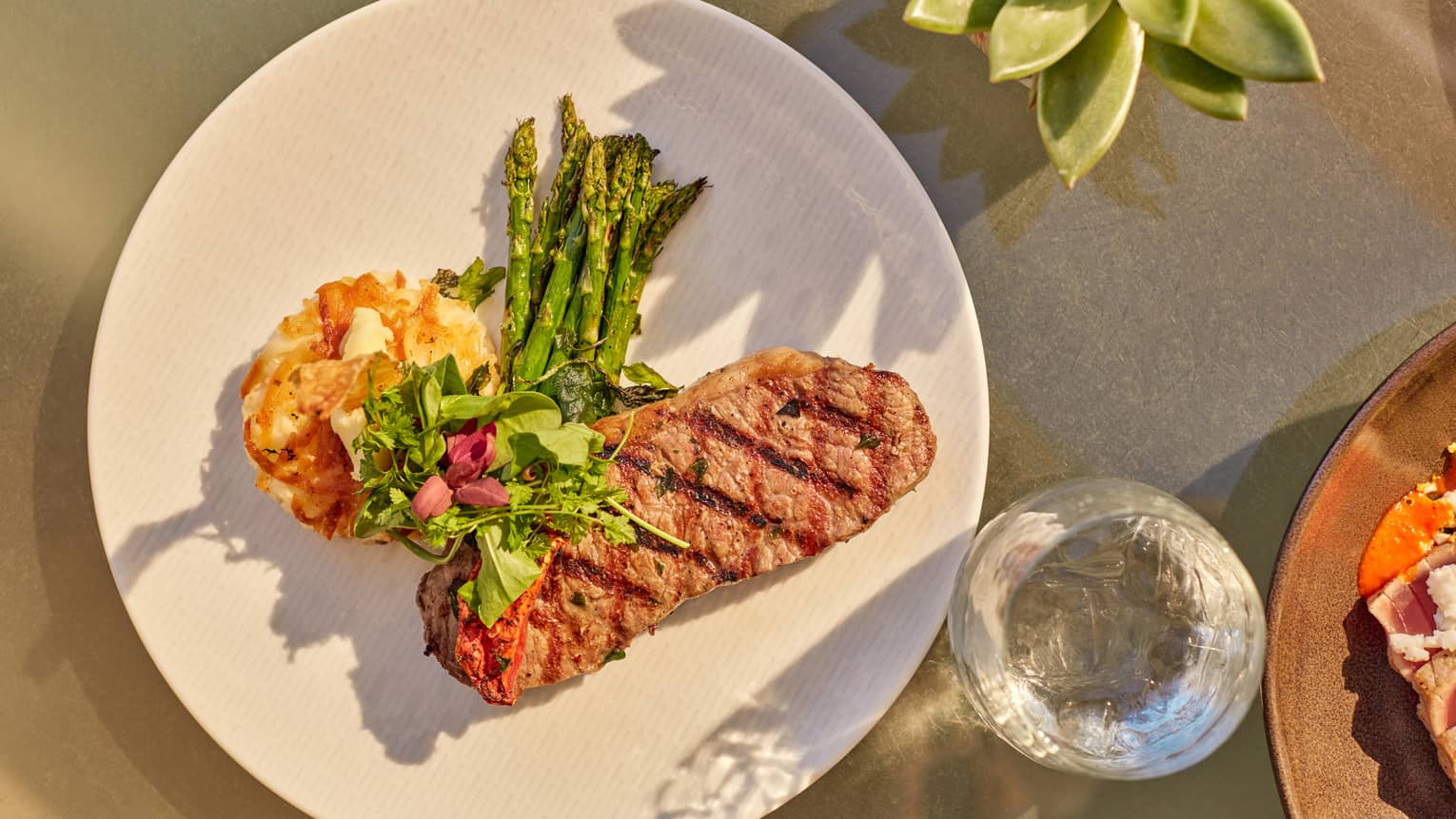Steak and eggs next to a glass of water.