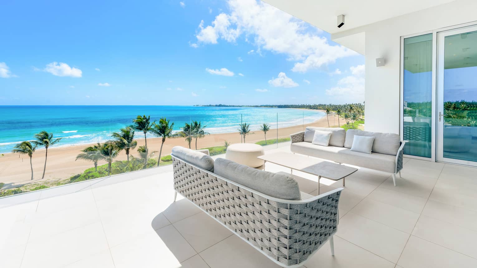 Outdoor living area with couches, beach and ocean in background