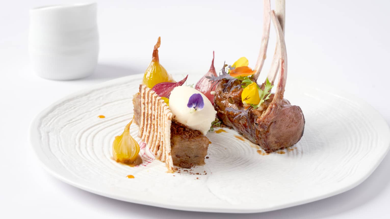 Gourmet rack of lamb topped with candied yellow beets, flowers