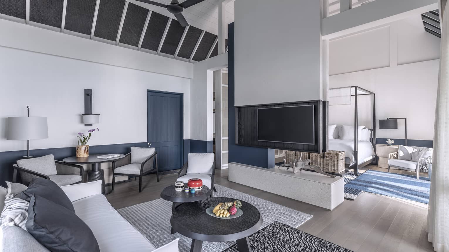 A brightly lit, cozy living room with a television, couch and access to the bedroom