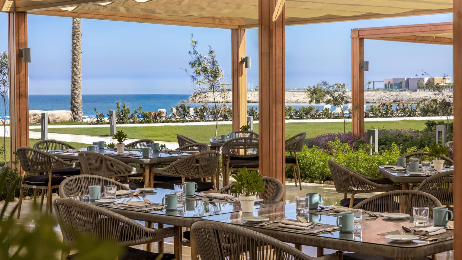 Beach Restaurant covered outdoor terrace with rattan dining chairs and views of the Mediterranean