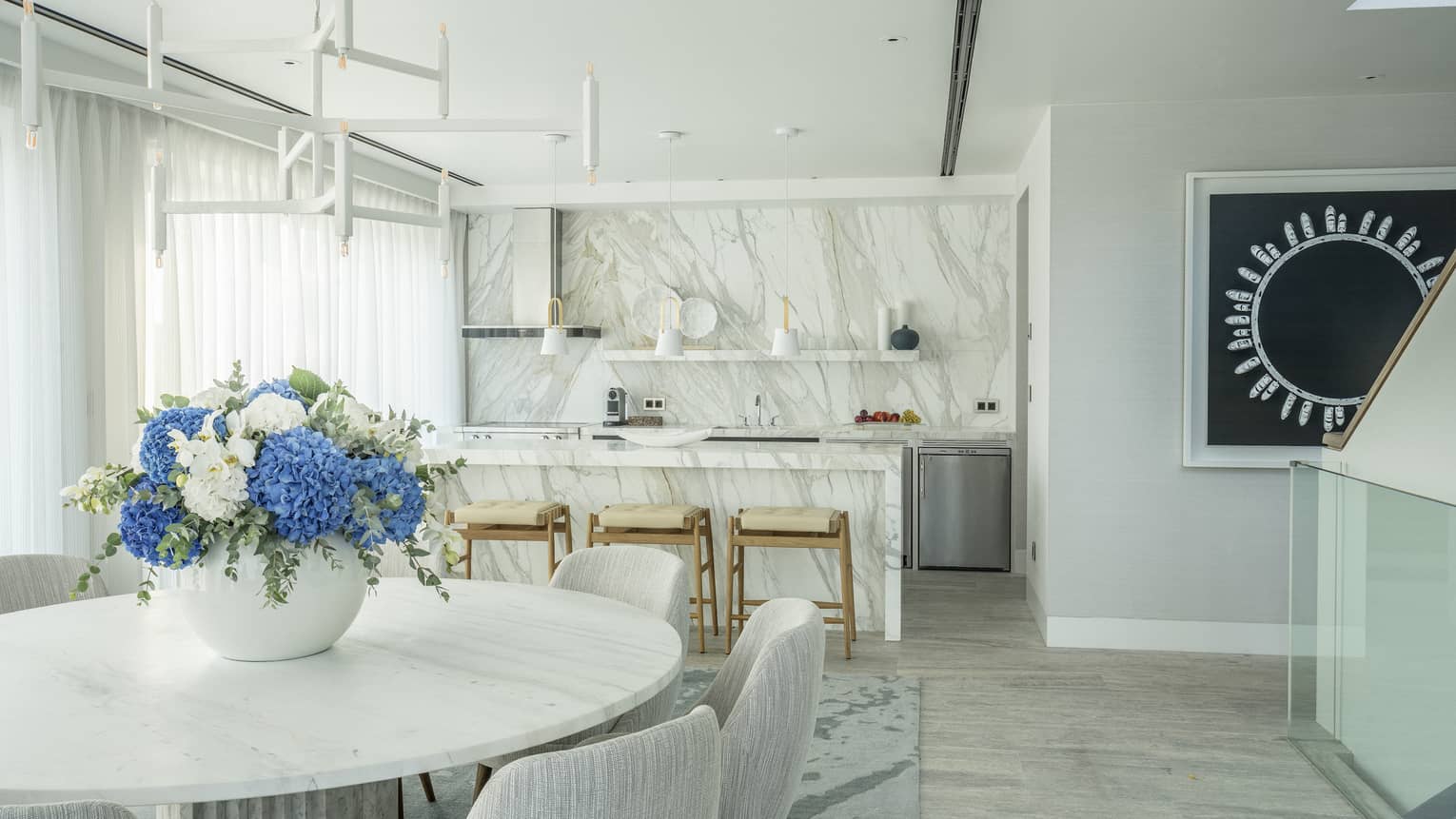 Arion Riviera Suite dining area with round table, white bucket chairs, marbled kitchen island with stools