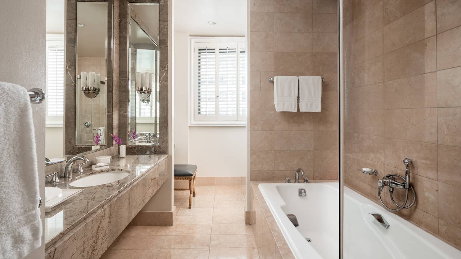 Bathroom with tub and marble vanity with one sink