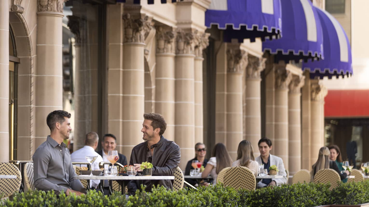 Small groups of people sitting and dining on an outside patio.