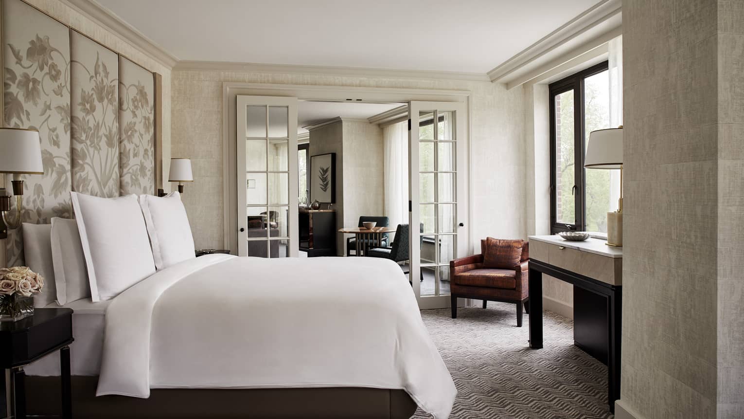 State Suite bedroom with white bed and fabric floral headboard, glass French doors to living room