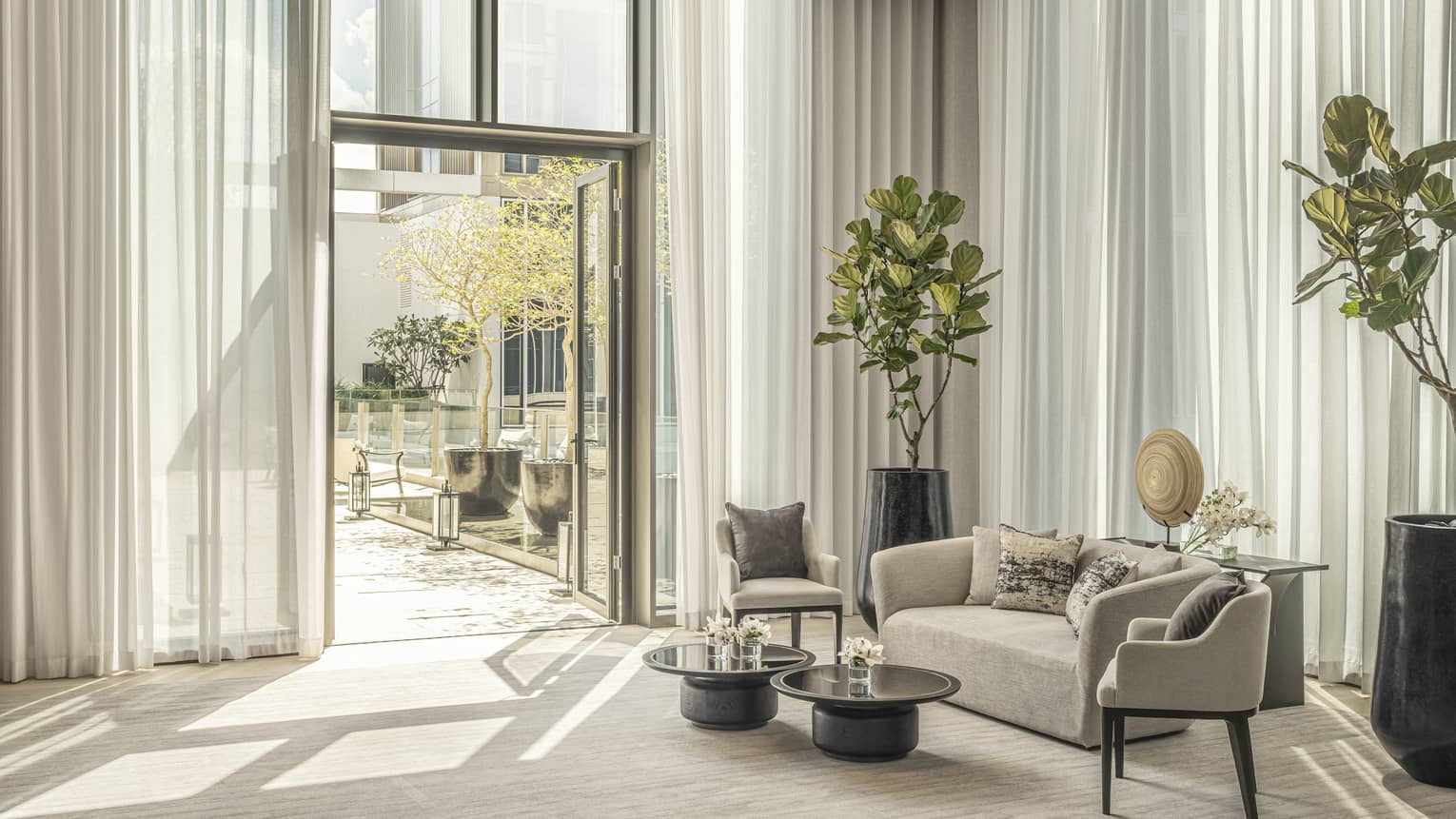 Conservatory garden terrace with cream-coloured carpet and matching sofa, potted green foliage, open door leading outside