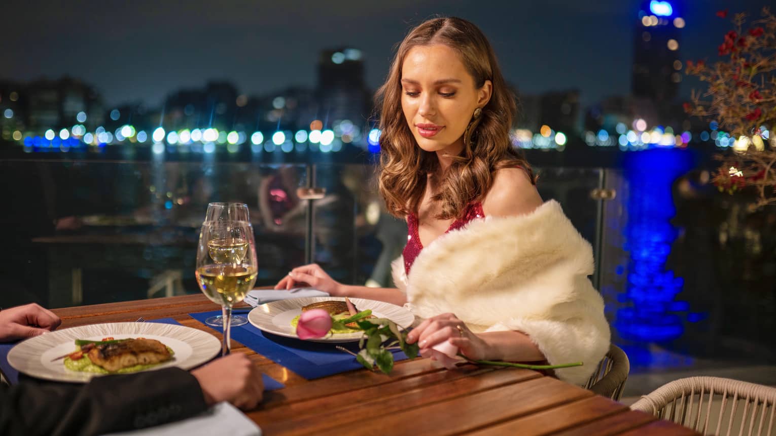 Woman enjoys meal outdoors, downtown Cairo visible in background