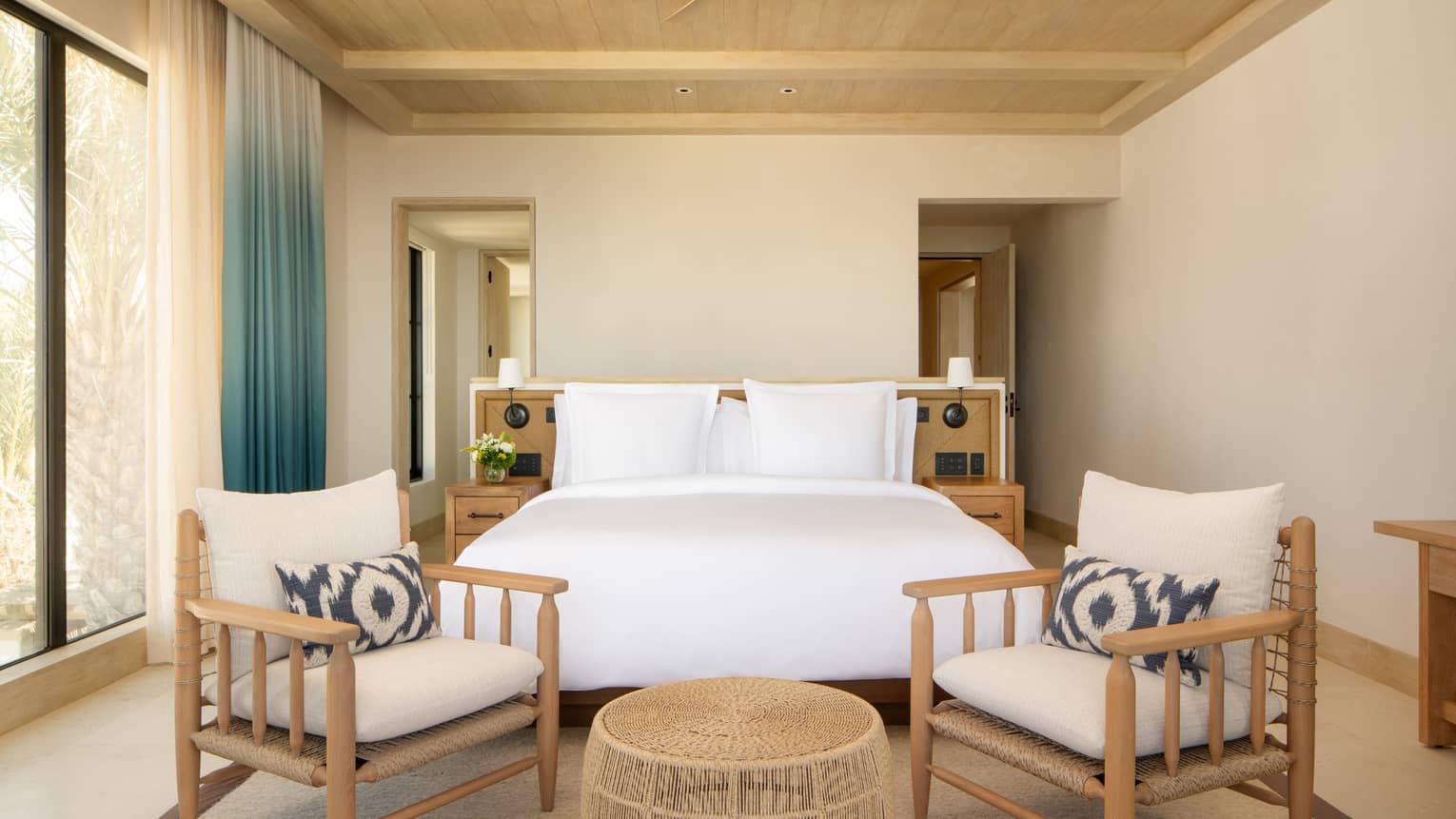 Luxury villa bedroom with king bed and two chairs, beamed ceiling, and windows, at Four Seasons Resort Cabo San Lucas at Cabo Del Sol