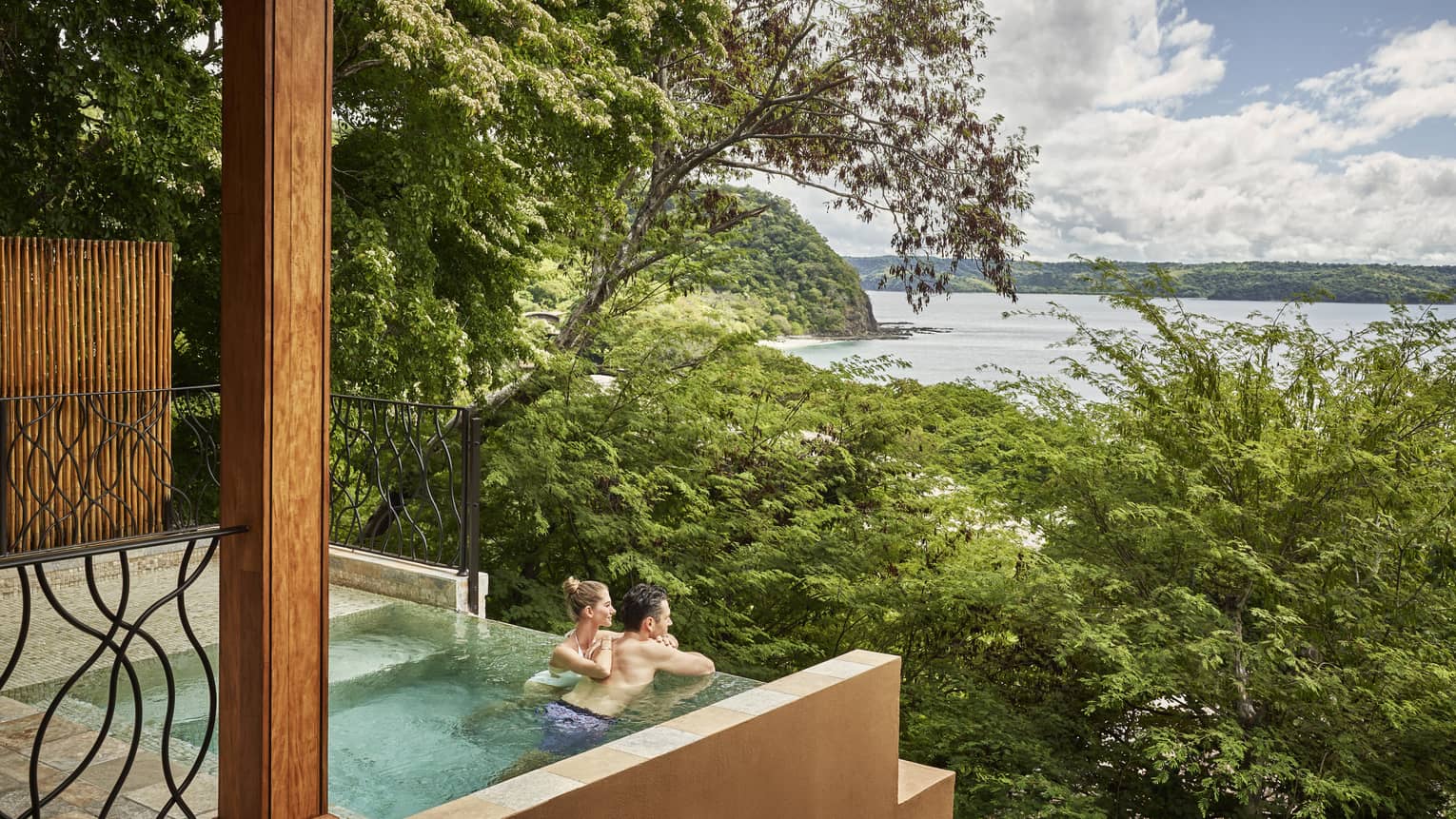 Couple in private plunge pool looking out to trees and ocean