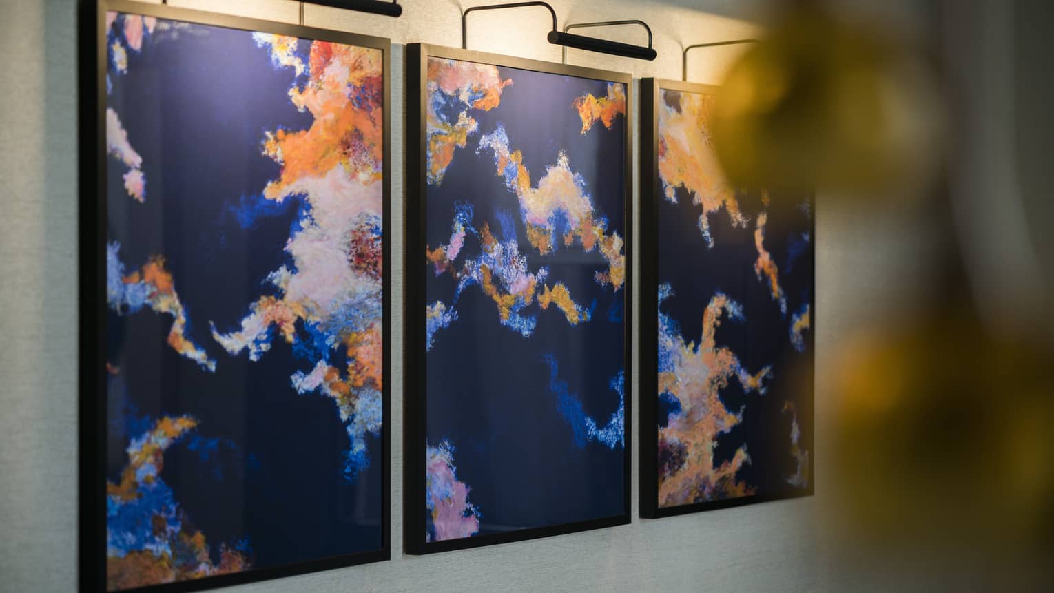 Brightly-coloured, three panel abstract painting on wall