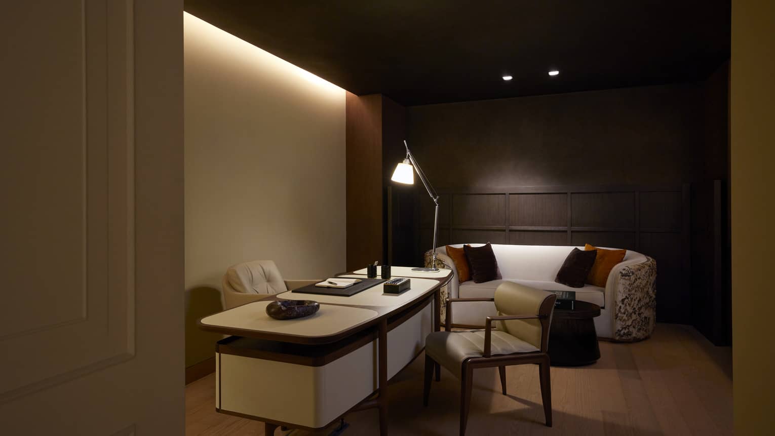 Office with dark wooden accent wall, sofa and desk