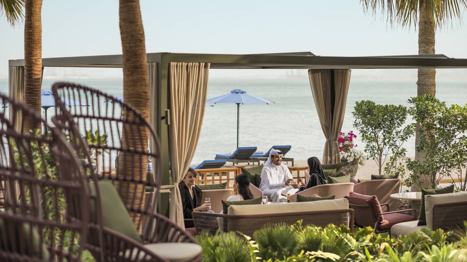 People sitting by the beach in an outdoor seating area in luxury hotel