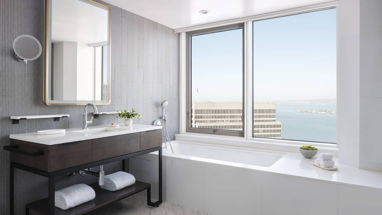 Bathroom with a sleek white built-in tub next to large window, modern wooden vanity 