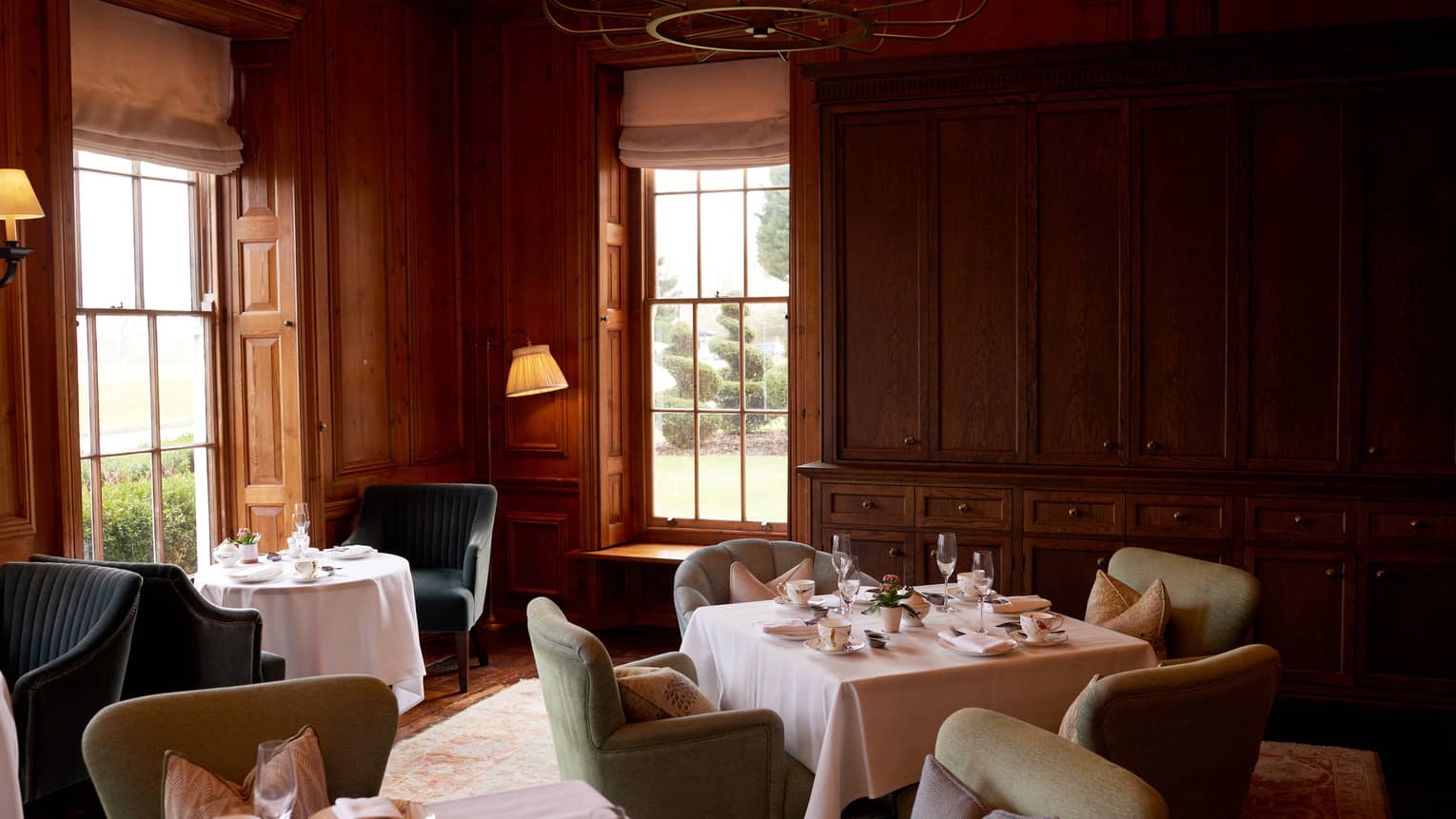 Cosy lounge with wood-panelled walls, small tables and chairs and dim lighting