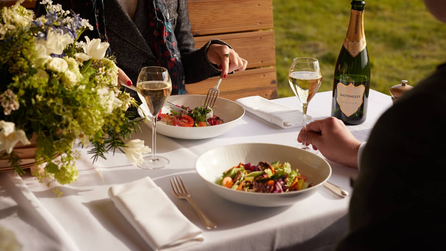 Two people seated outside, enjoying a meal with champagne