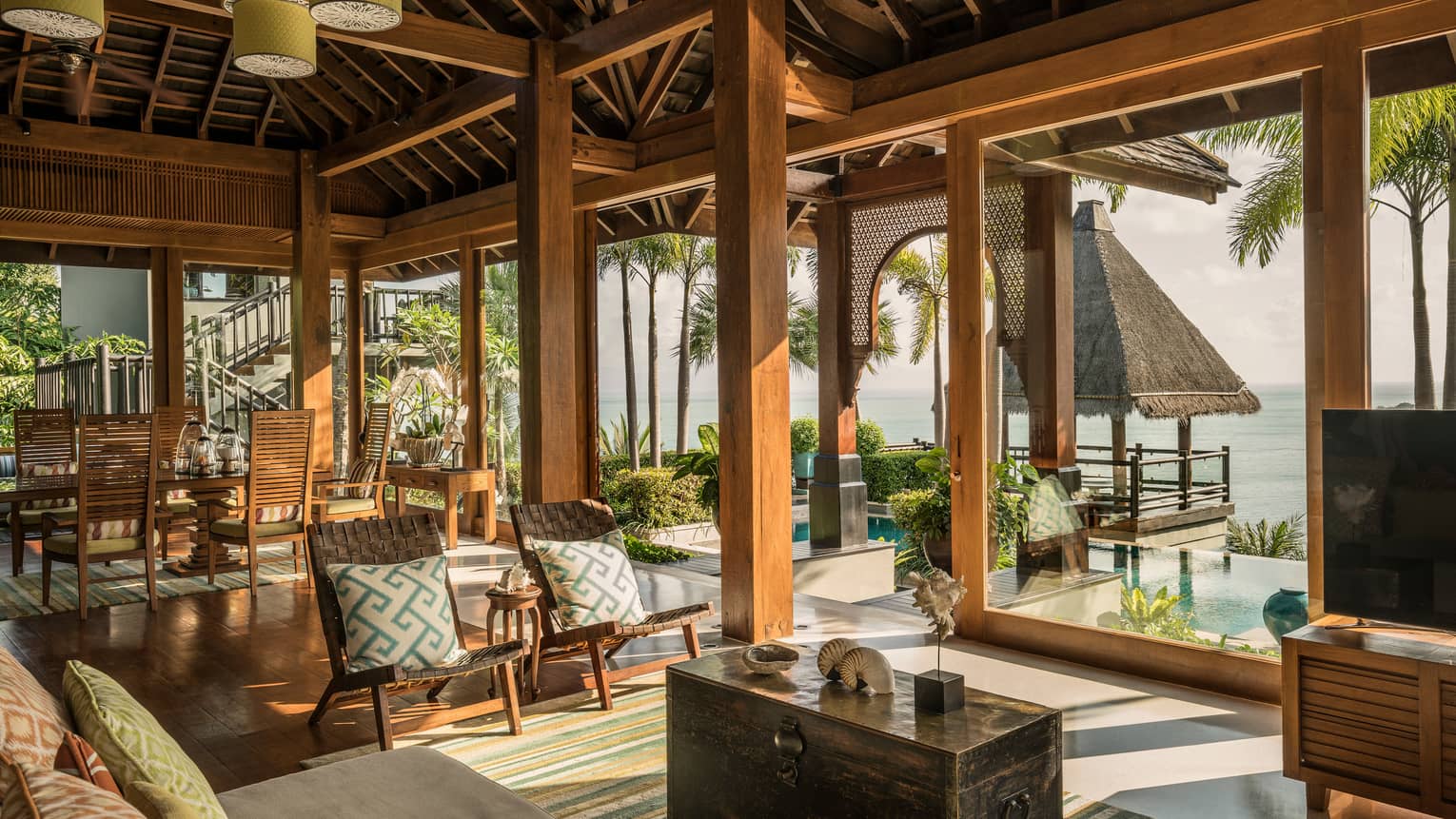 Bright, open air living and dining room, seats under rustic wood beam ceilings