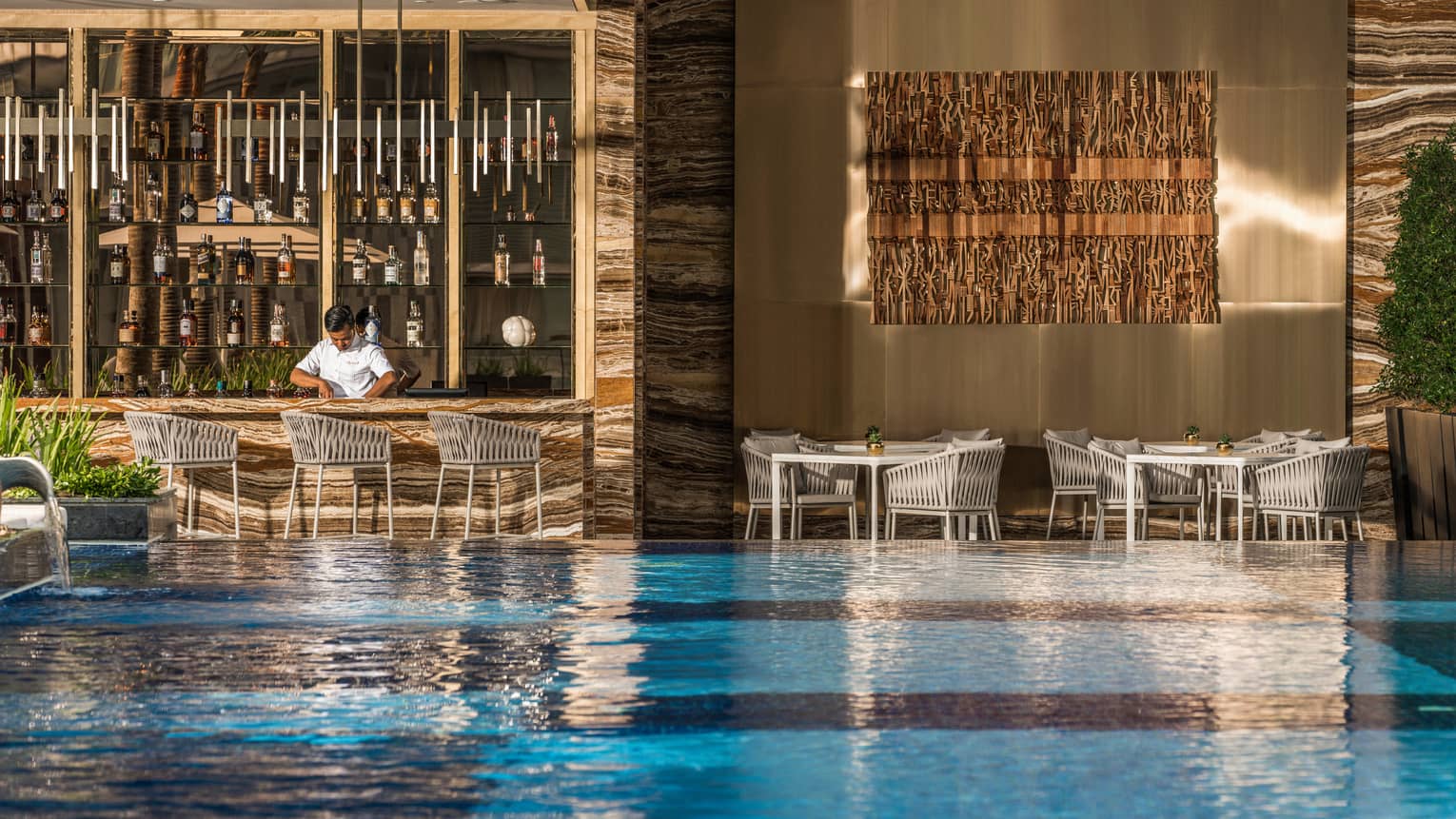 Pool bar and grill with view of pool and bartender