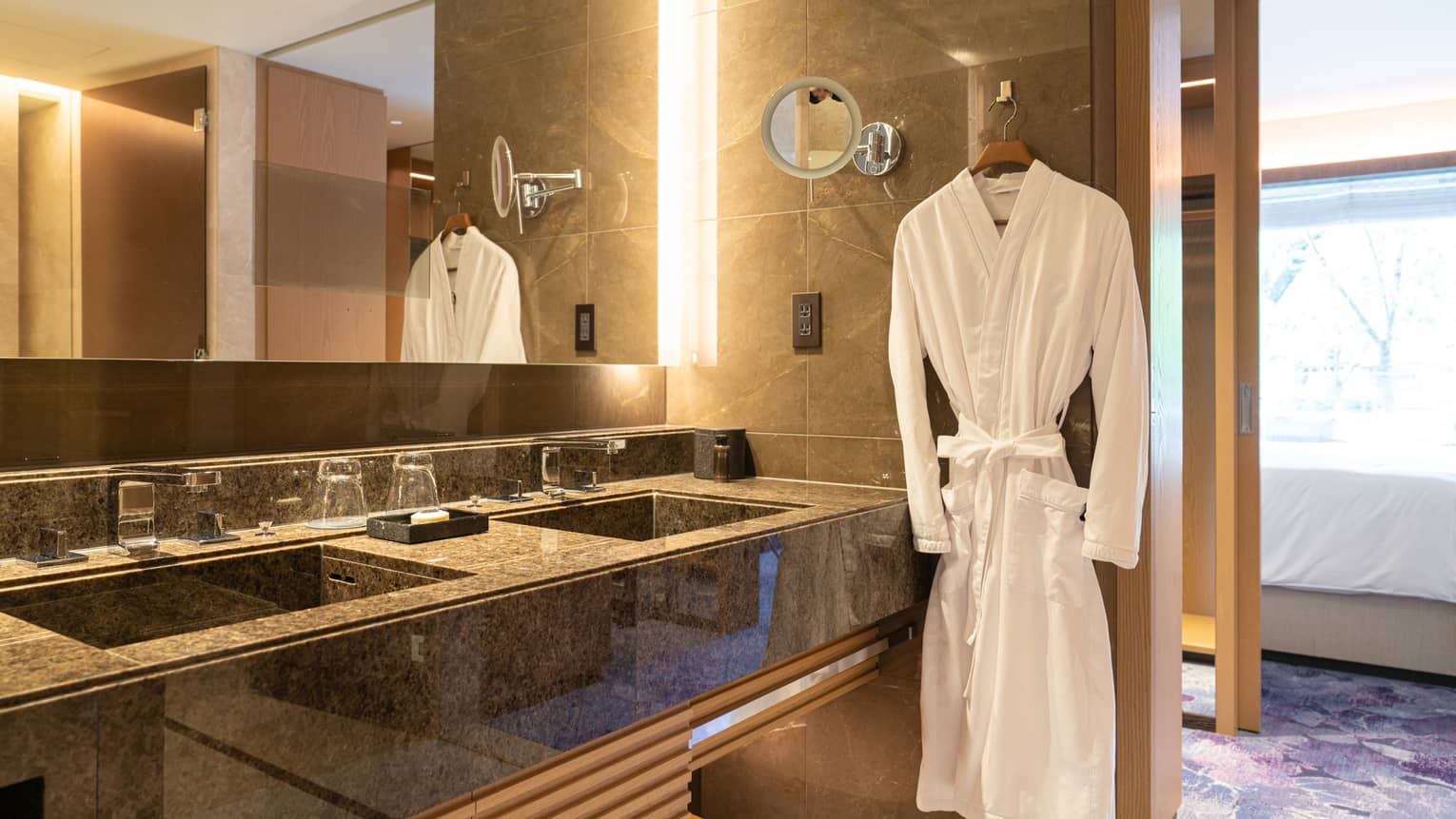 Luxury bathroom with a double-sink vanity, large mirror and a plush white robe hanging beside the counter