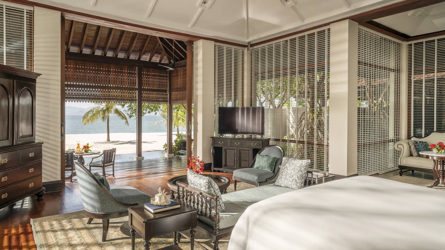 Bedroom with chaise and two arm chairs, plus opening to covered terrace and beach