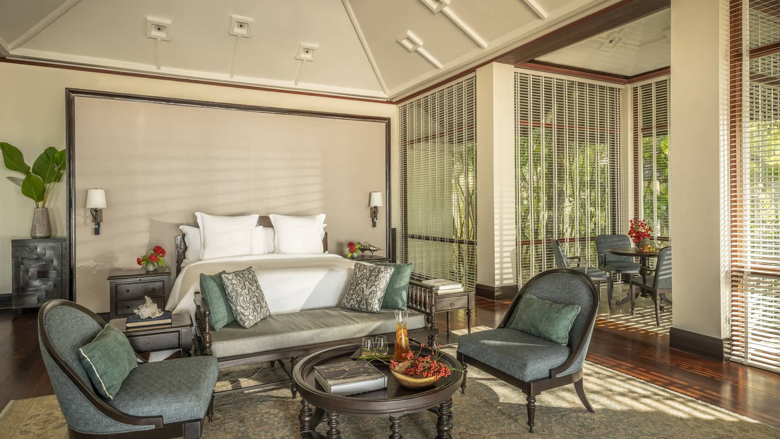 Large bedroom with king bed, wall-sized headboard, vaulted ceiling and coffee table with two arm chairs