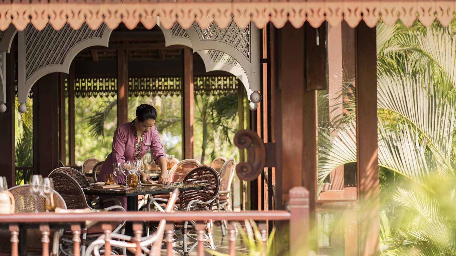 A Four Seasons staff setting the table in the open-aired Ikan Ikan at Four Seasons Langkawi