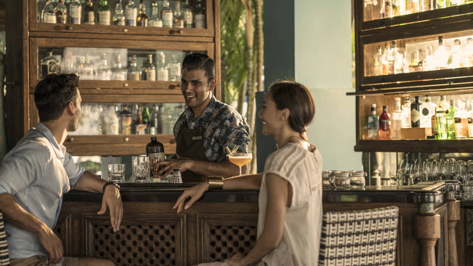 Two guests chat with a bartender at rhu bar while he makes a drink