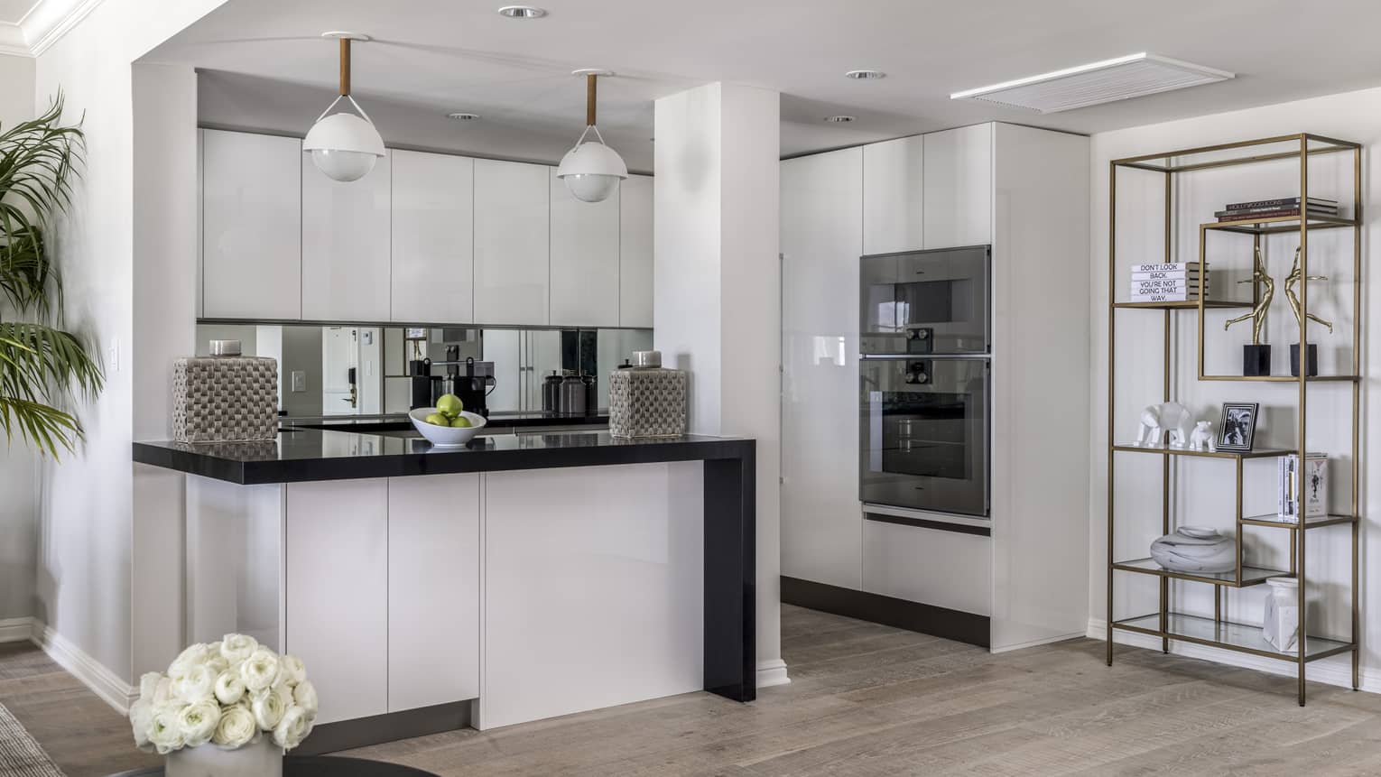 Kitchen with white cupboards, black counter, two hanging lights