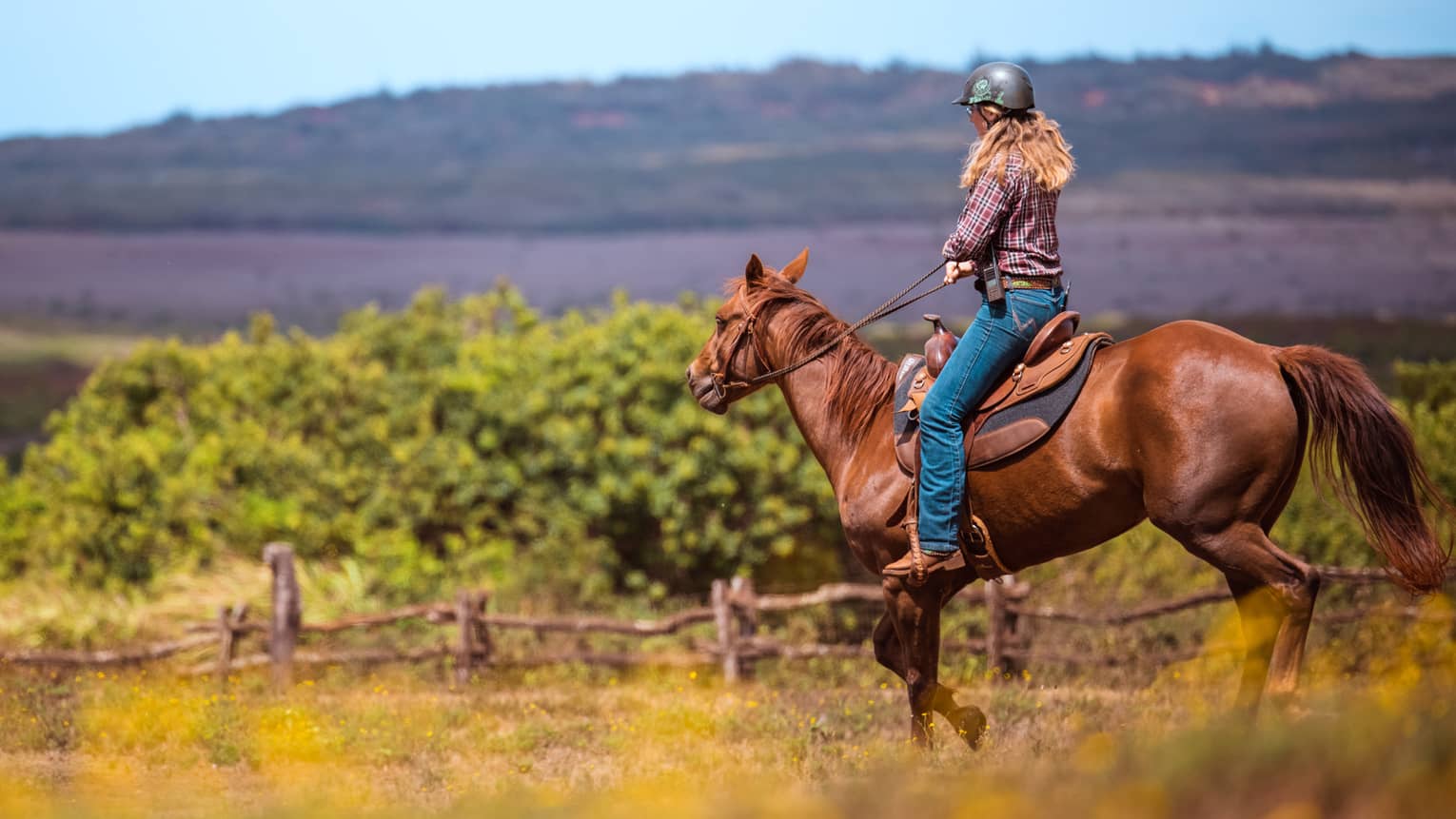 A woman horseback riding in a mountain landscape