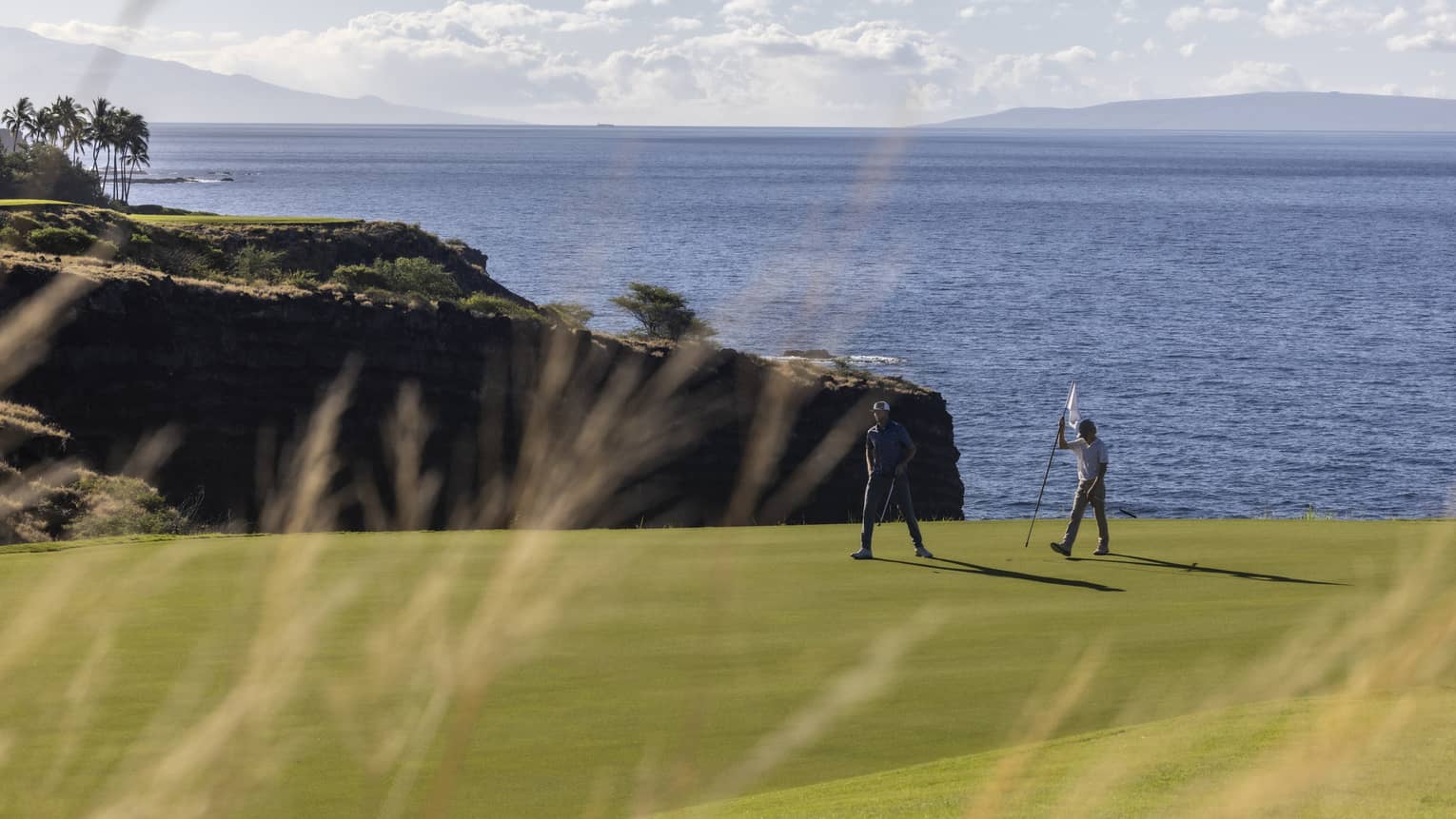 Two golfers on oceanside green at Four Seasons Resort Lanai