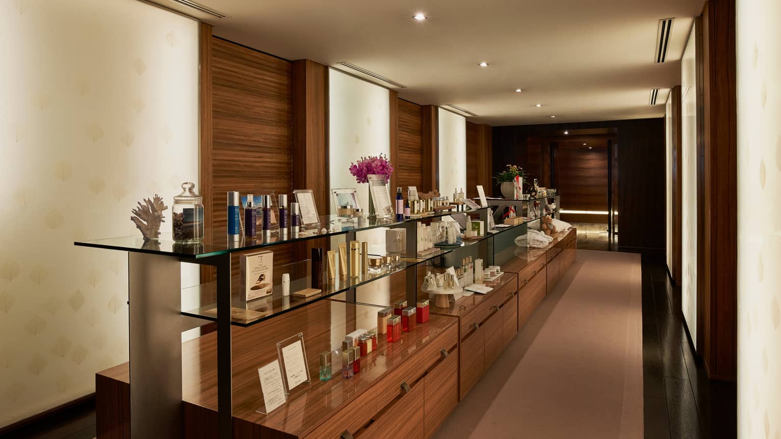 Wood and glass display shelves with boutique items in dimly lit hallway