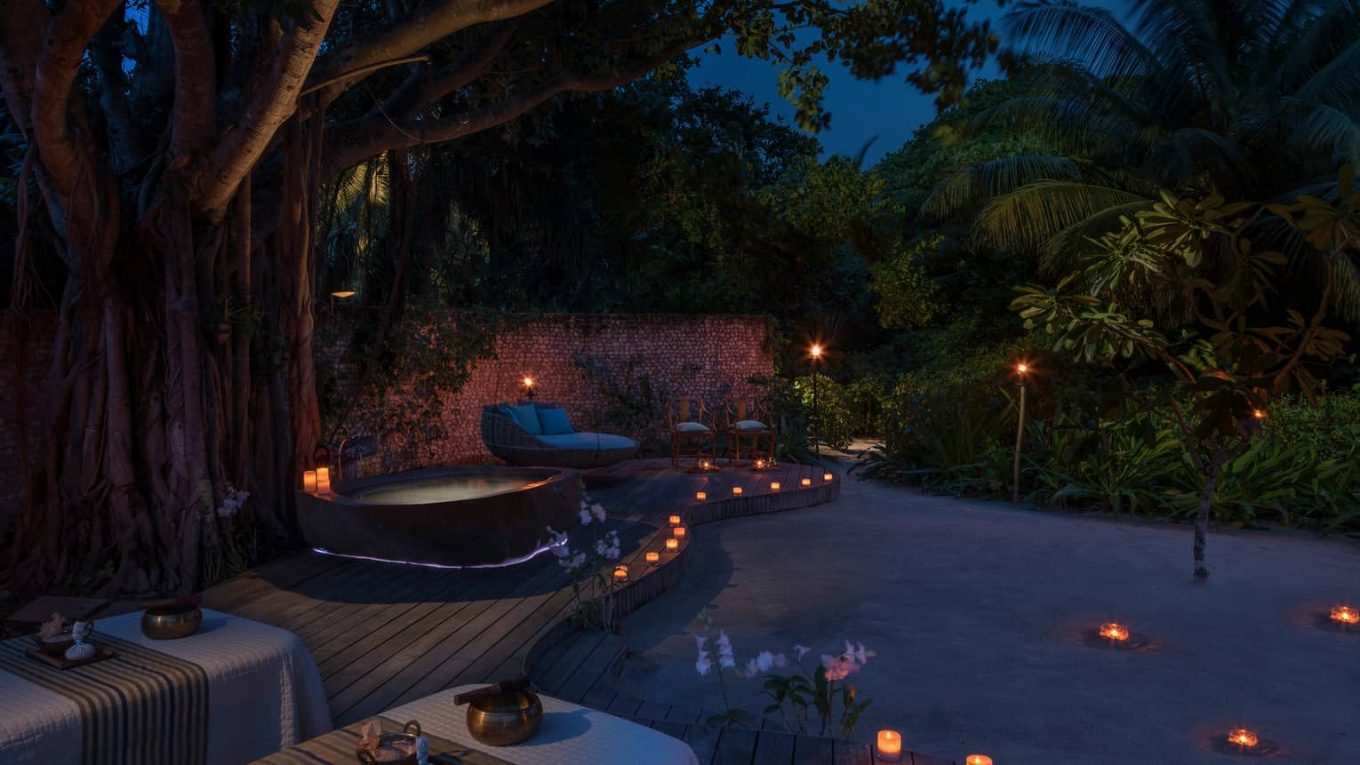 Candles along sand beach, spa patio, hot tub at night