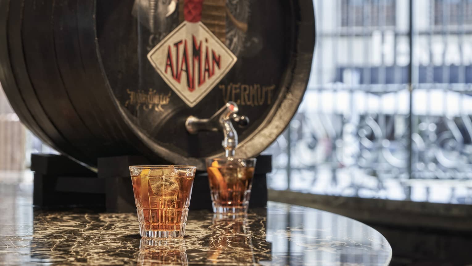 Vermouth cask with two filled cocktail glasses on marble table