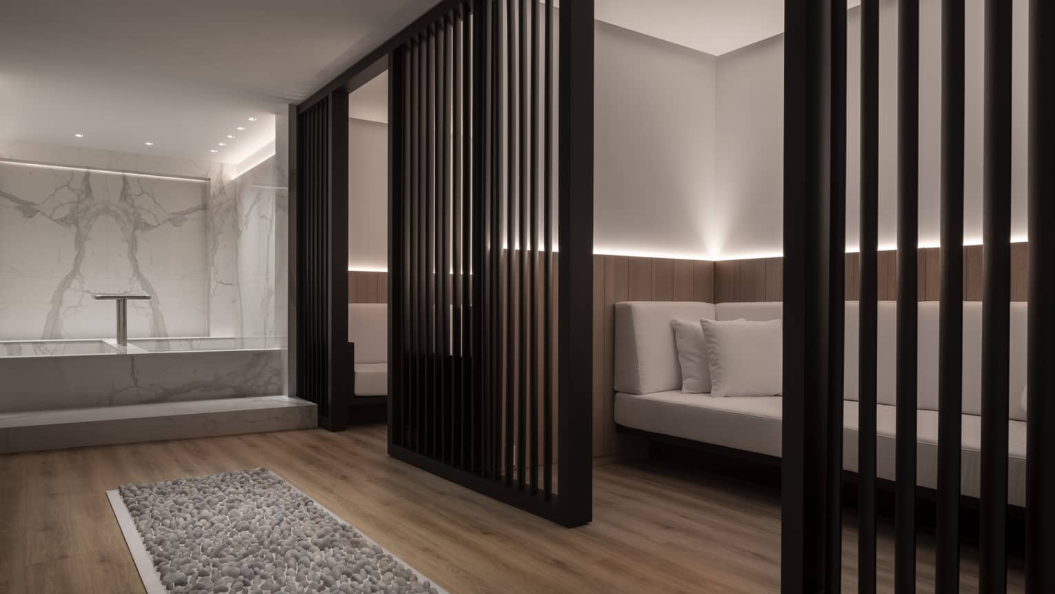 A long white couch obscured by a black privacy wall. 