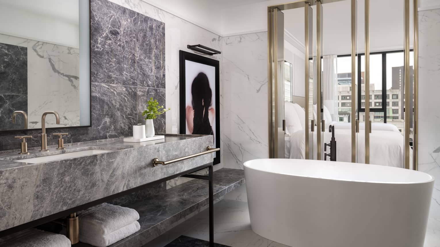 Spa-like guest bathroom with large white soaker tub, grey marbled vanity, modern artwork 
