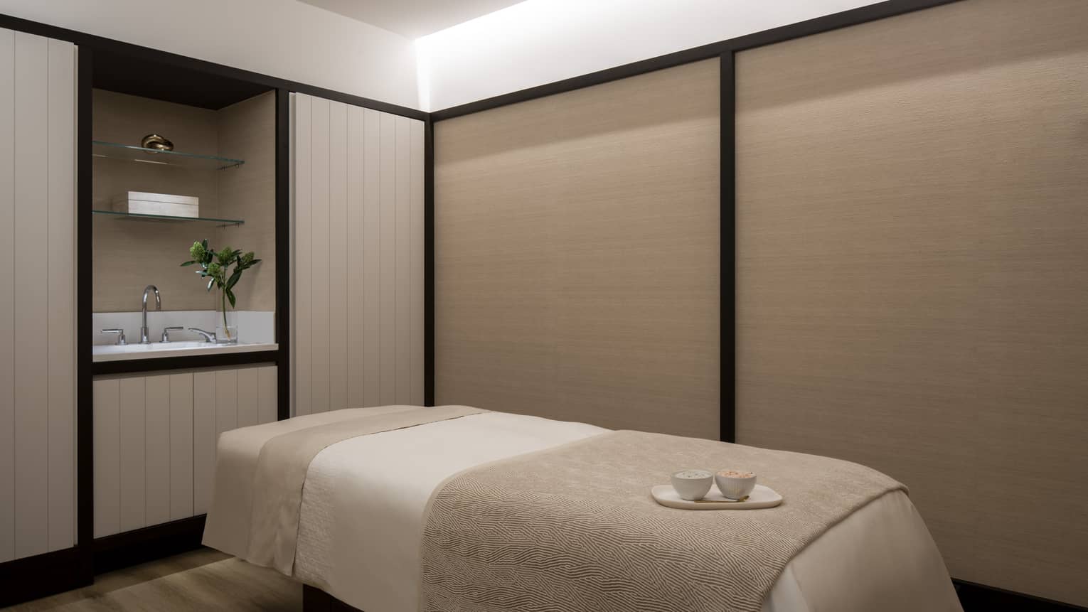 A beige massage bed with two teacups resting upon it. 