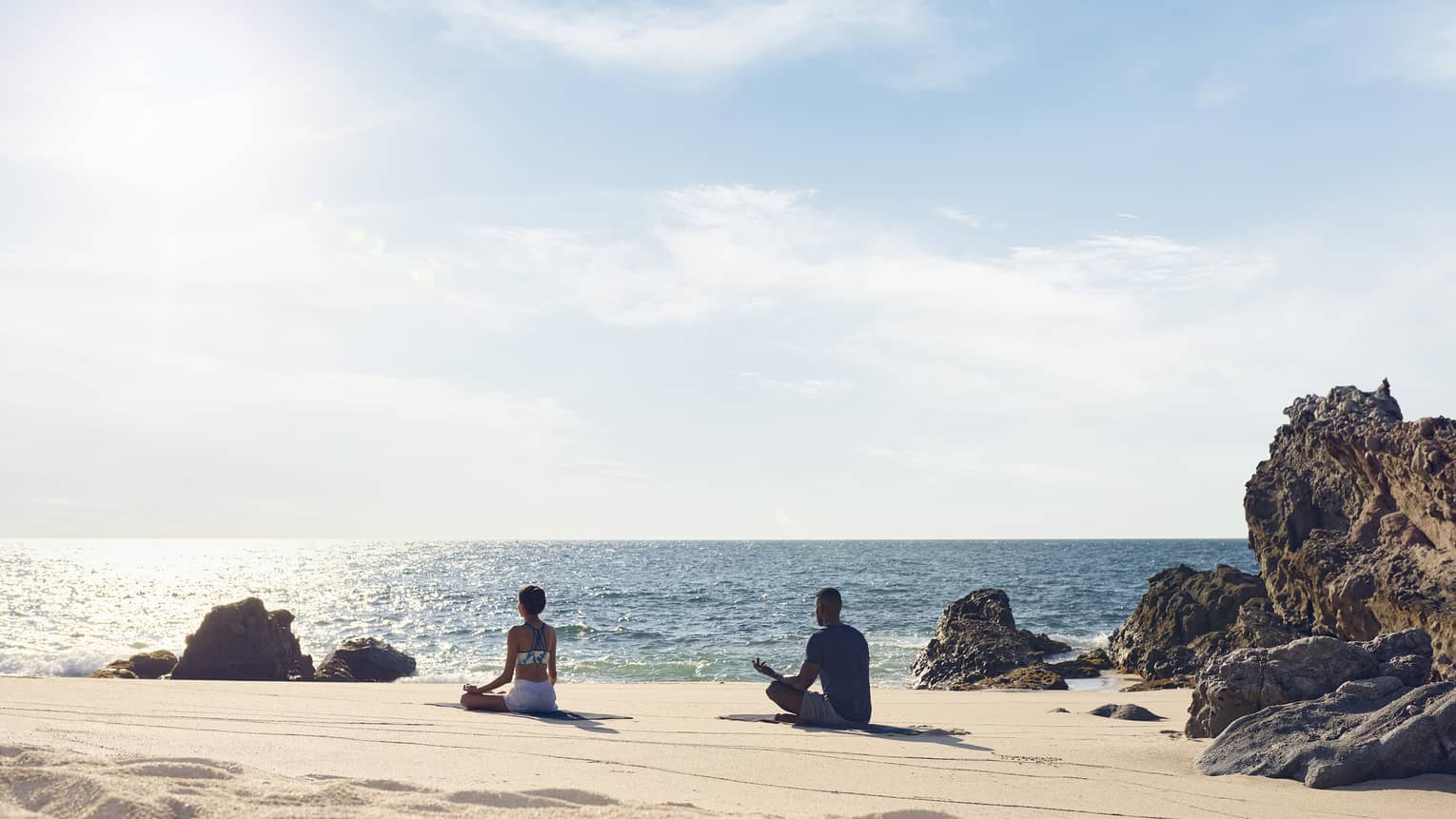 Two people meditate on a beach in Punta Mita