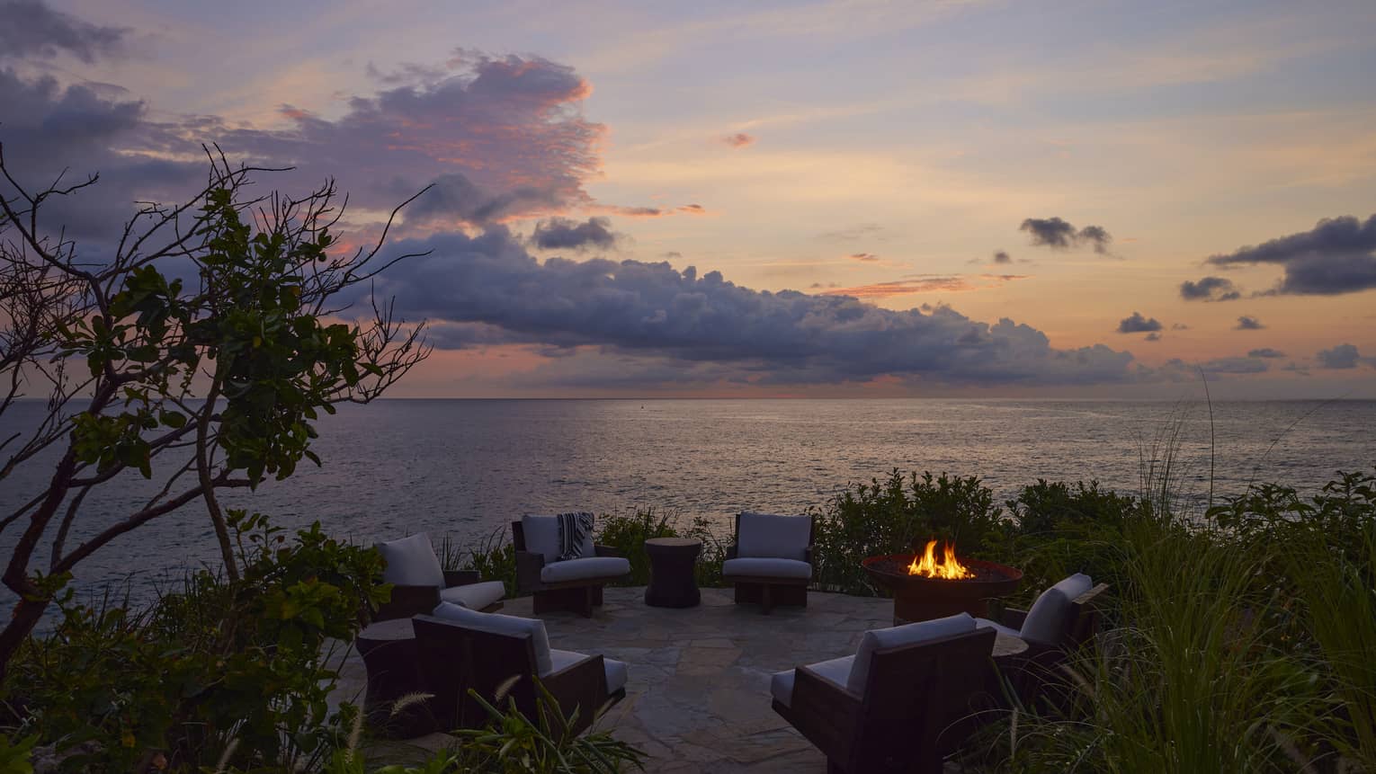 Bonfire pit with cushioned chairs by the ocean