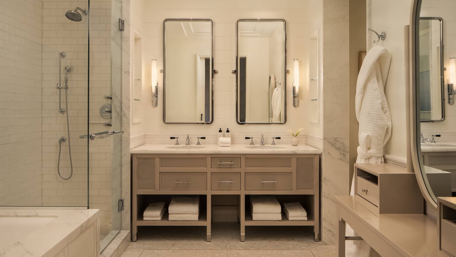 Luxury hotel bathroom with double vanity, glass-enclosed shower and bath tub