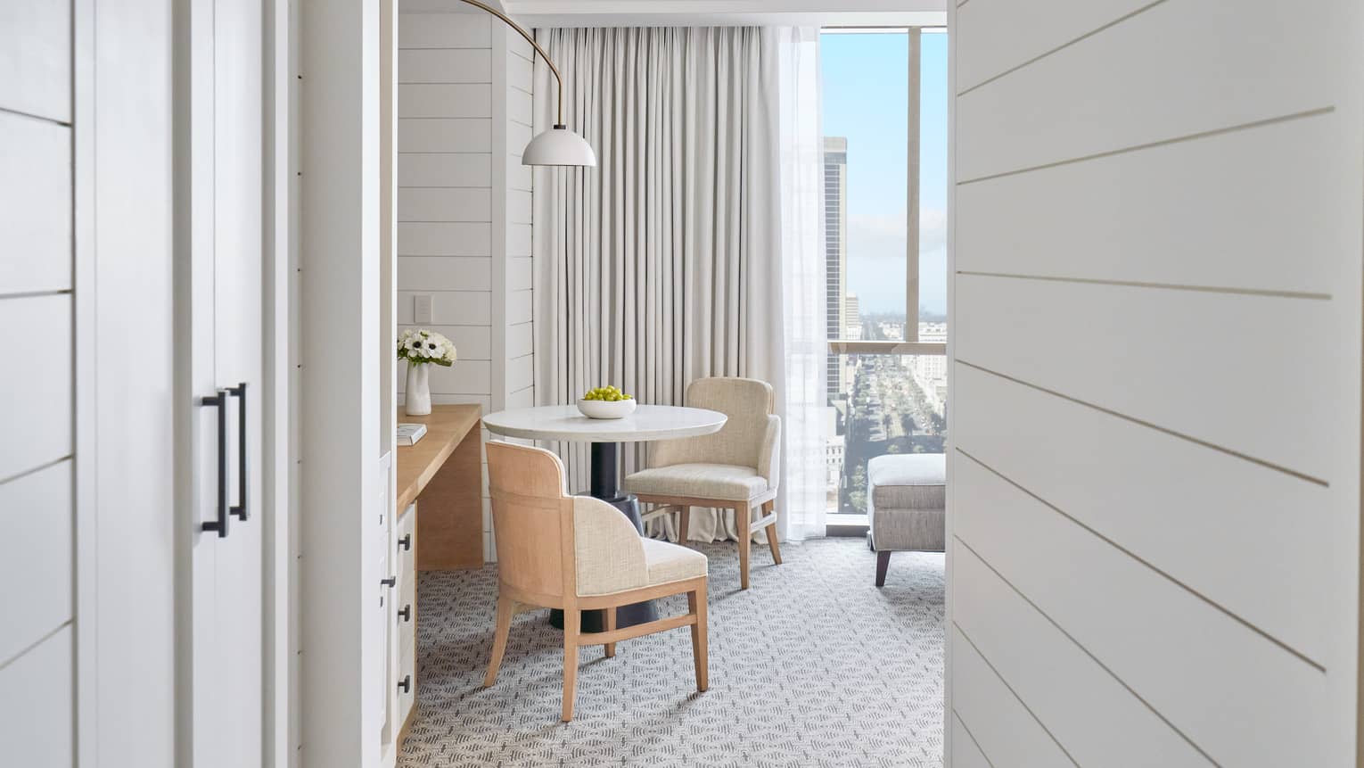 Deluxe City-View Room sitting area with round table and two chairs, hanging floor lamp, floor-to-ceiling windows