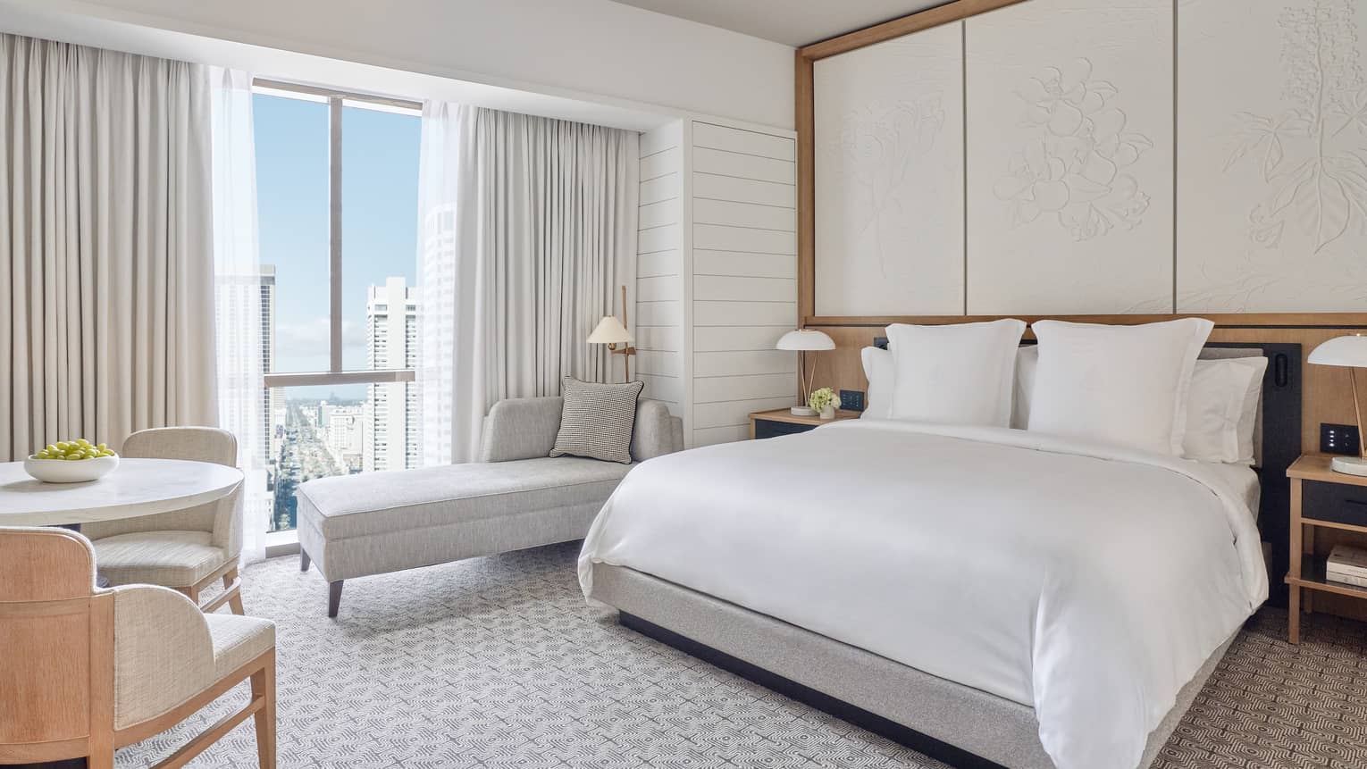 Luxurious room featuring a king-size bed, elegant décor and a stunning city view from large windows.