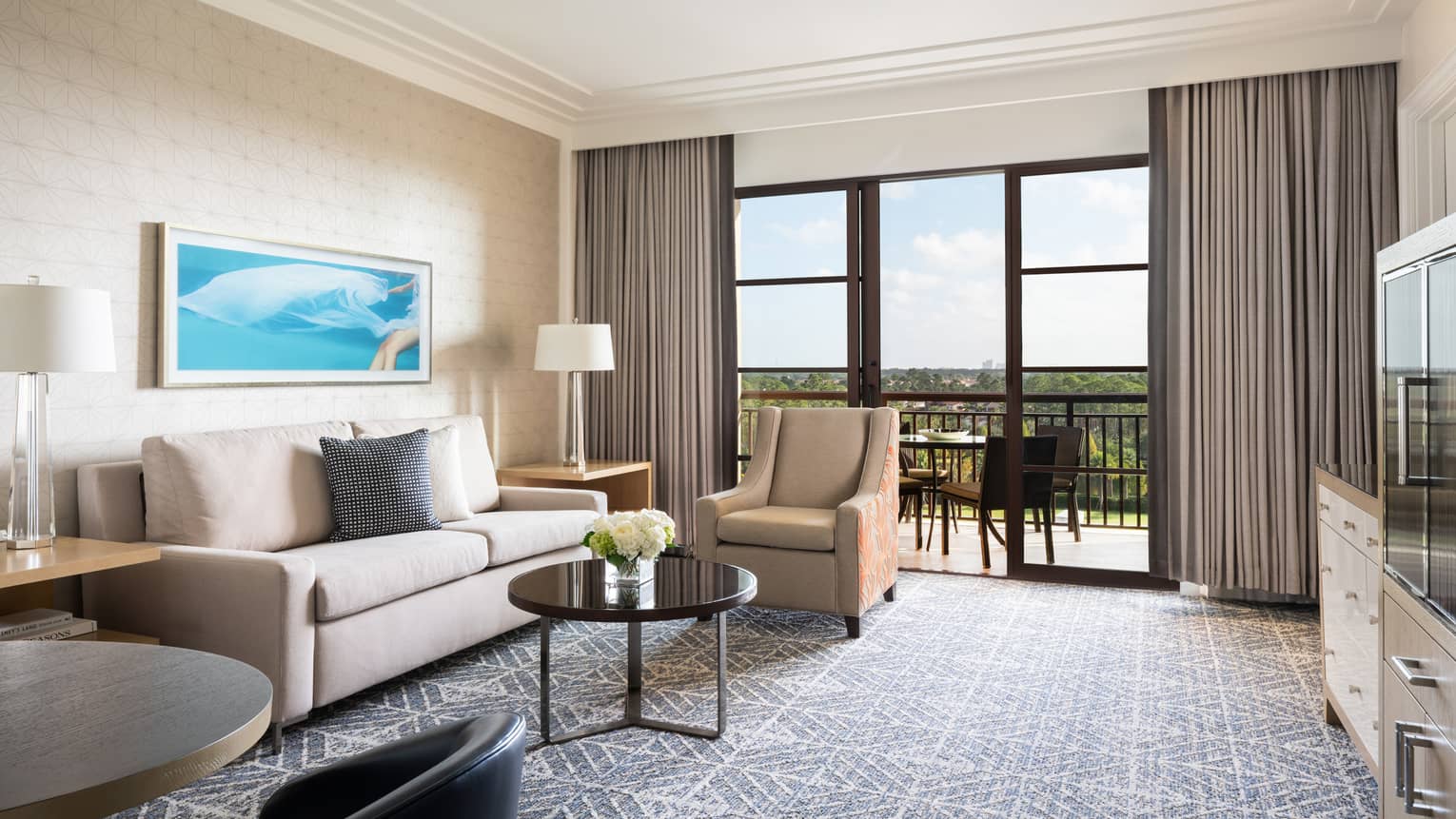 Living room with beige sofa, tan armchair, coffee table, walk-out balcony, grey carpet