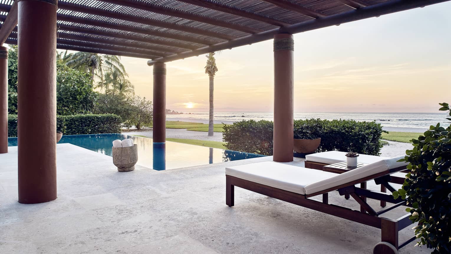 Outdoor terrace with lounge chairs, private pool, sun setting over the sea