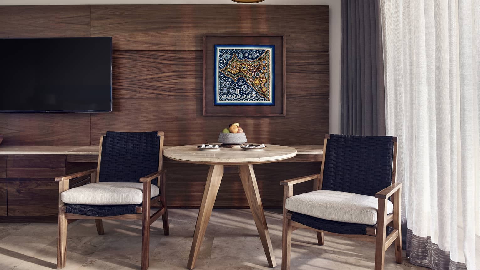 Small wooden table and two arm chairs, wooden wall and artwork