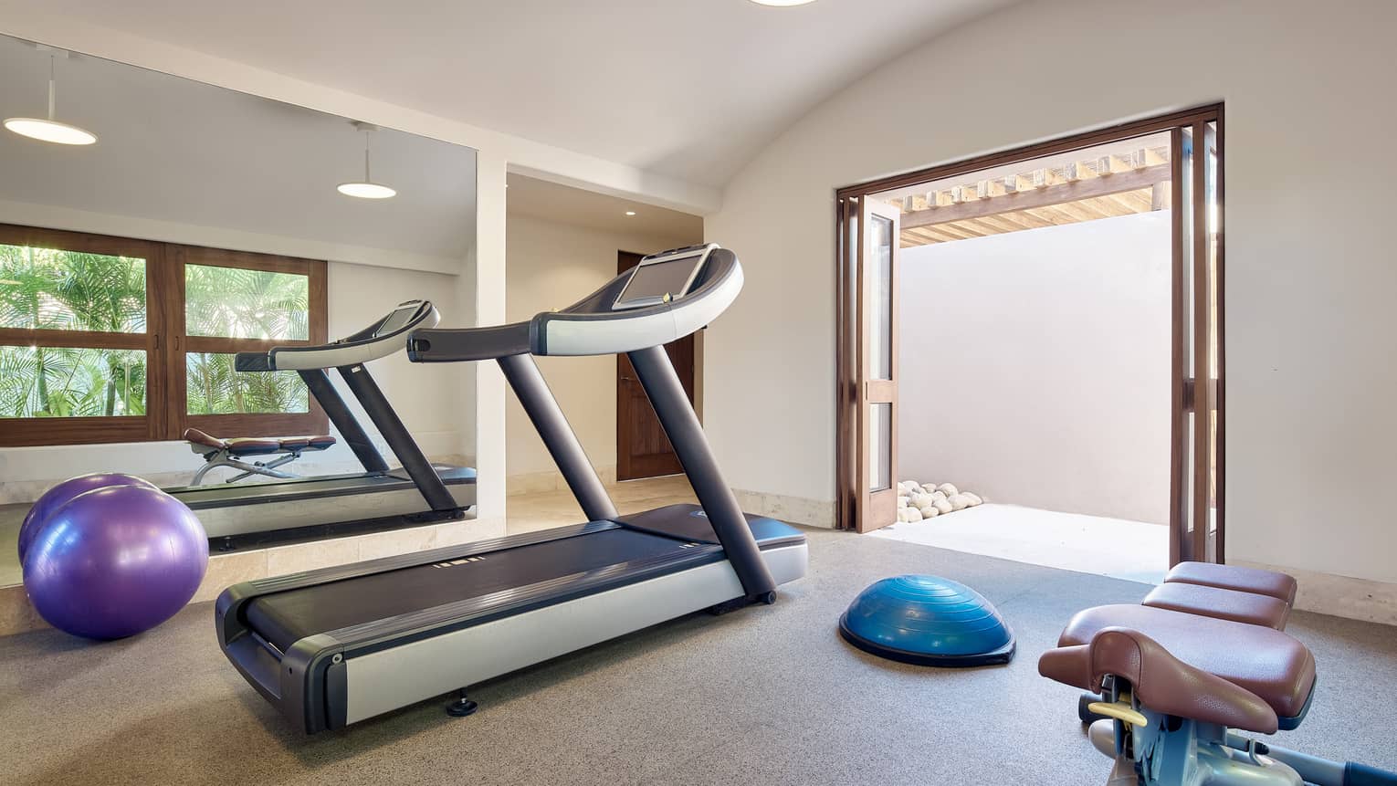 Coral Beach House private fitness room with treadmill, exercise ball, full mirrored wall, door opening to patio
